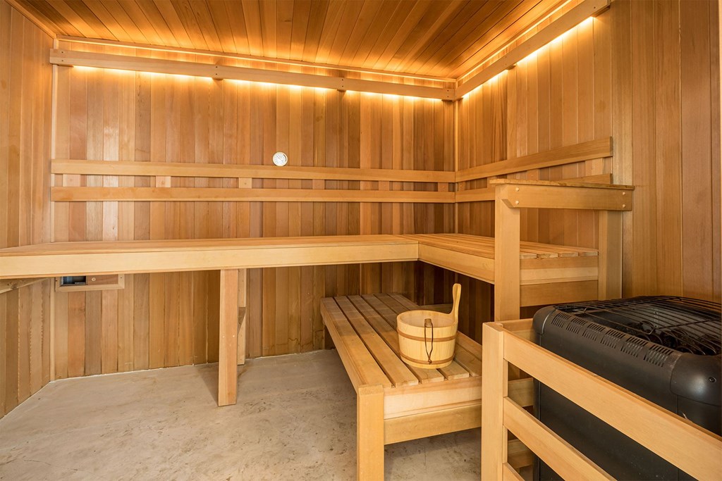 A wooden sauna with benches and a bucket.