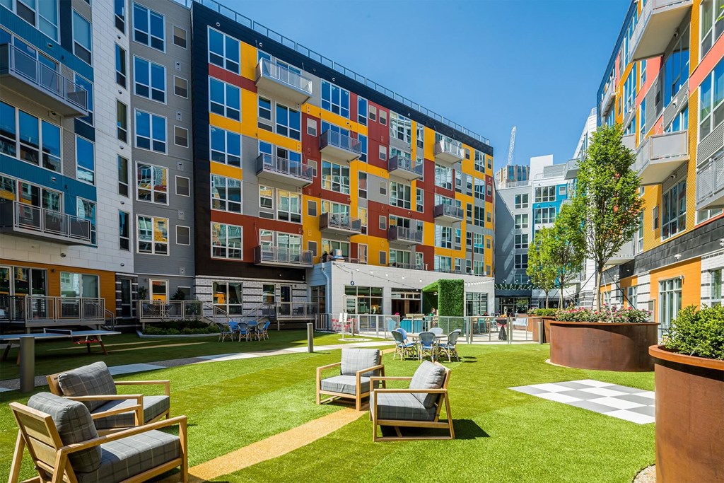A sunny day at a colorful apartment complex with a grassy courtyard.