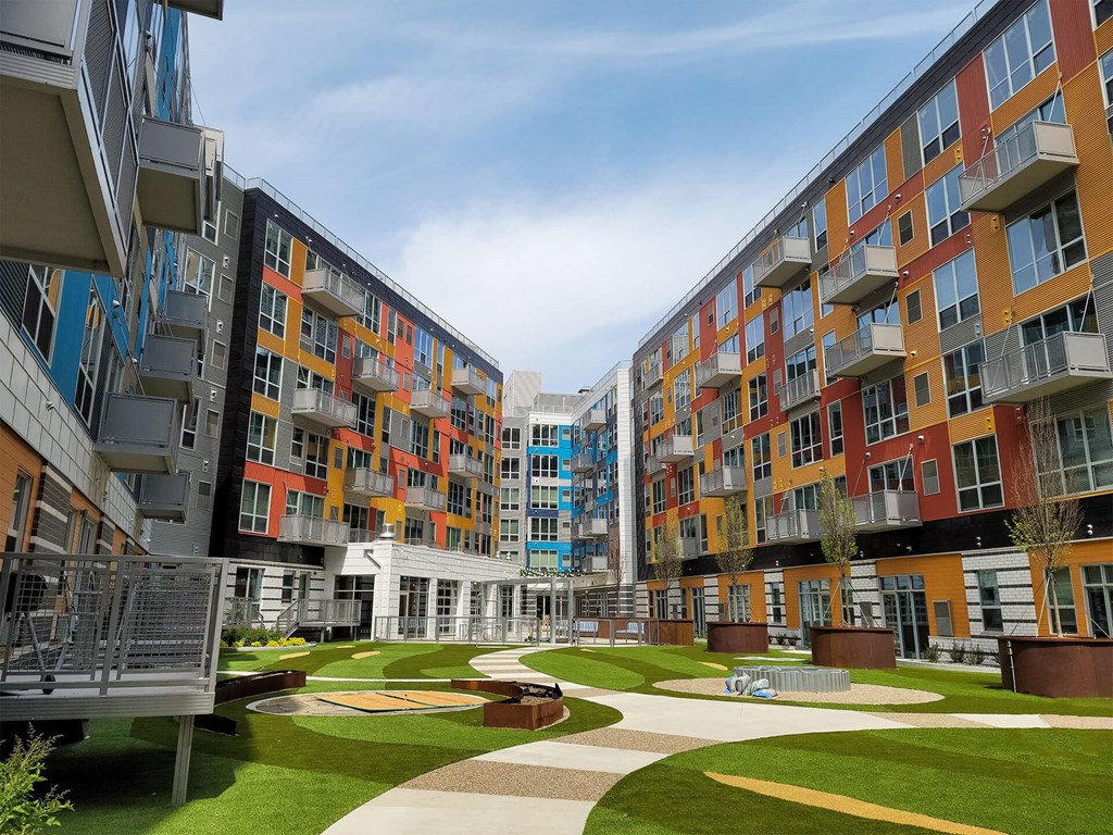 A modern apartment complex with a green lawn in the courtyard.