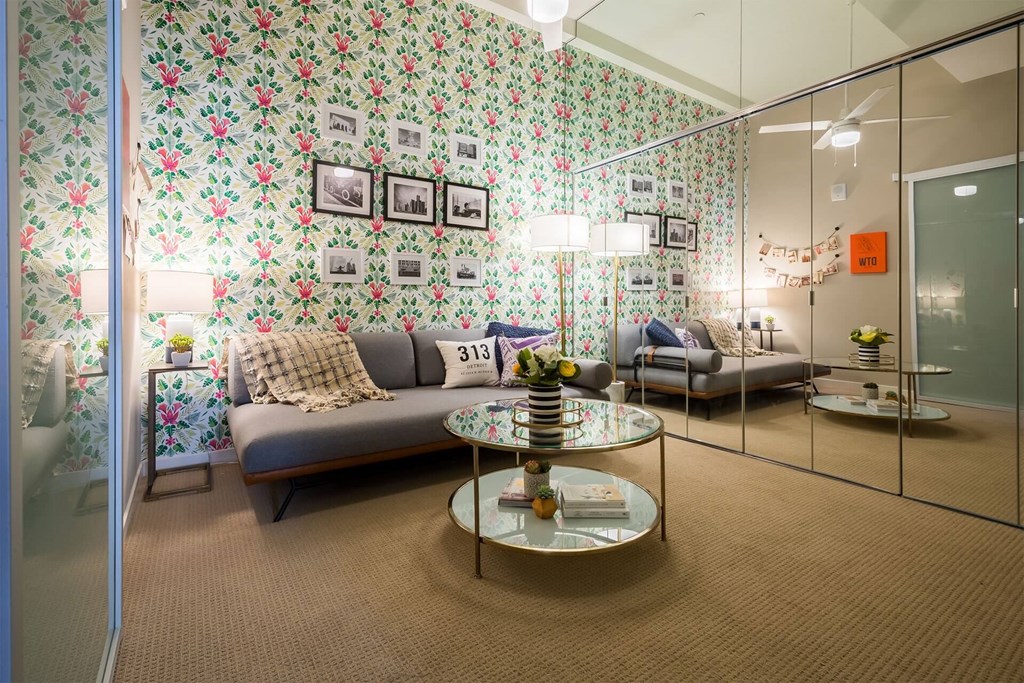 A living room with a grey couch and a glass table.