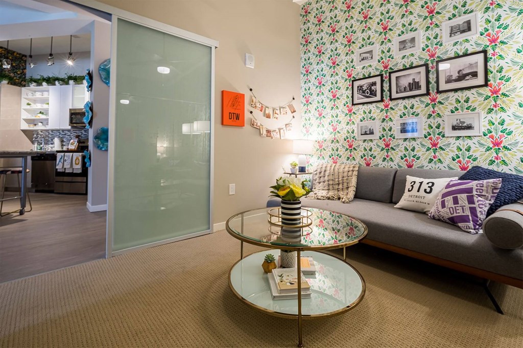 A living room with a grey couch and a glass coffee table.