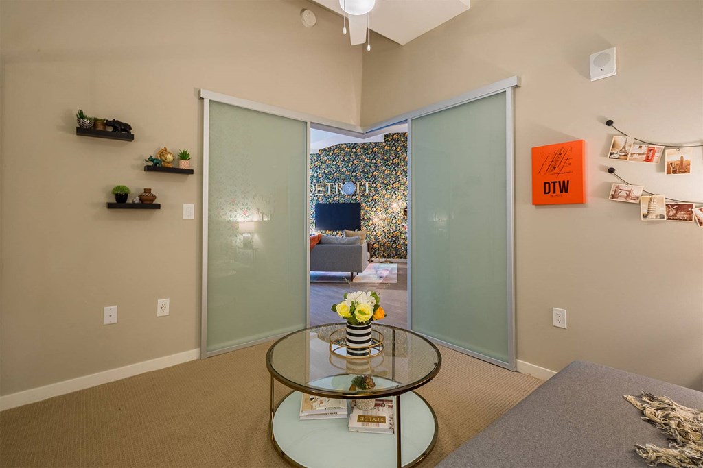 A glass table with a vase of flowers on it sits in a room with a sliding glass door.