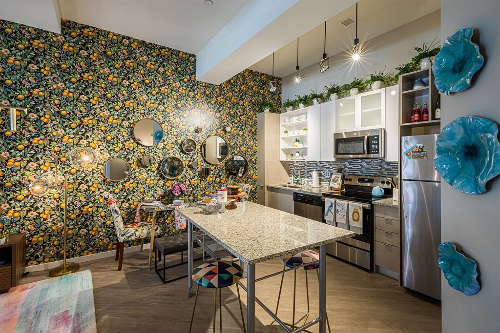 A kitchen with a table and chairs in front of a wall covered in flowers.