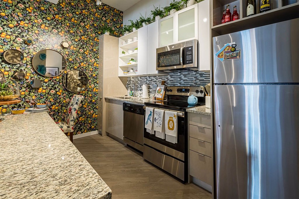 A kitchen with a stainless steel refrigerator and a floral wallpaper.
