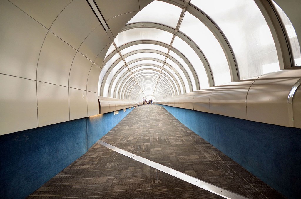 a tunnel with blue walls and white light at the end