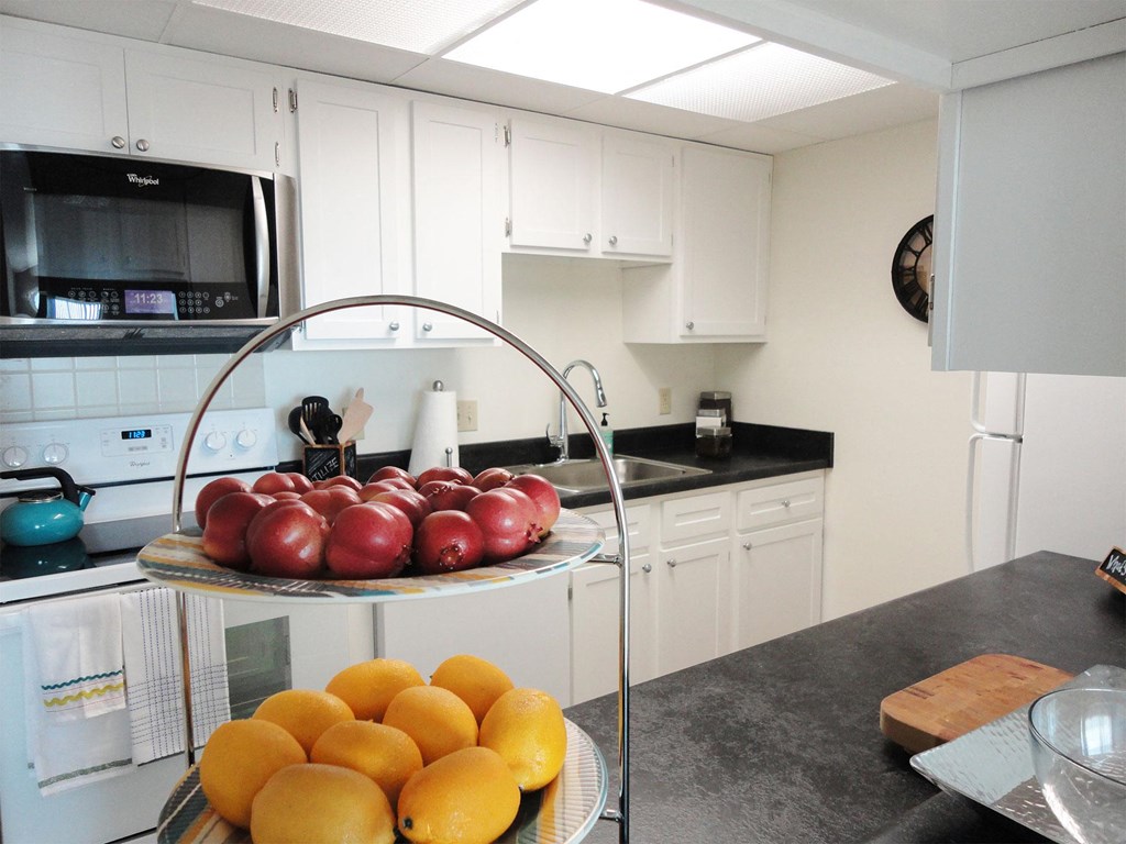 a kitchen with white cabinets and a bowl of fruit on a counter