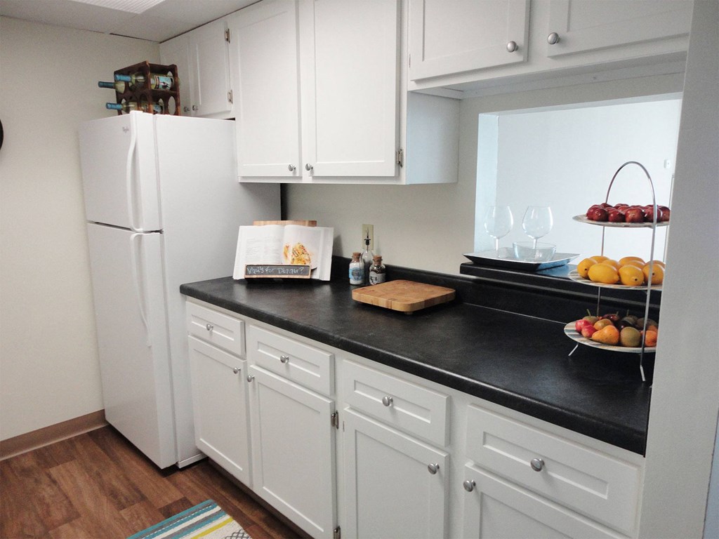 a kitchen with white cabinets and a black counter top