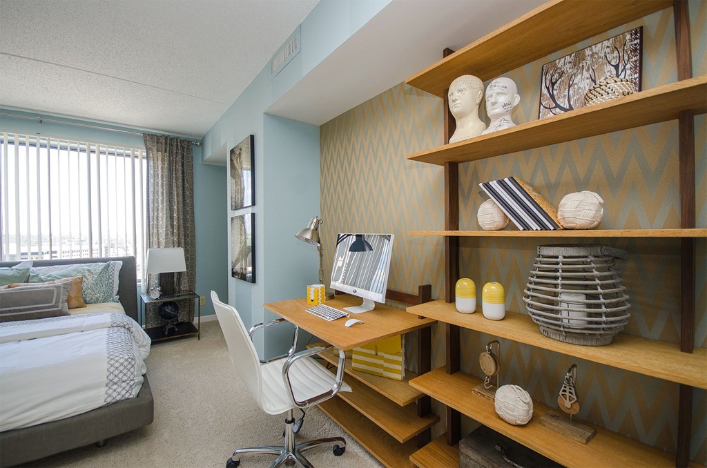 a bedroom with a desk with a computer and a bed