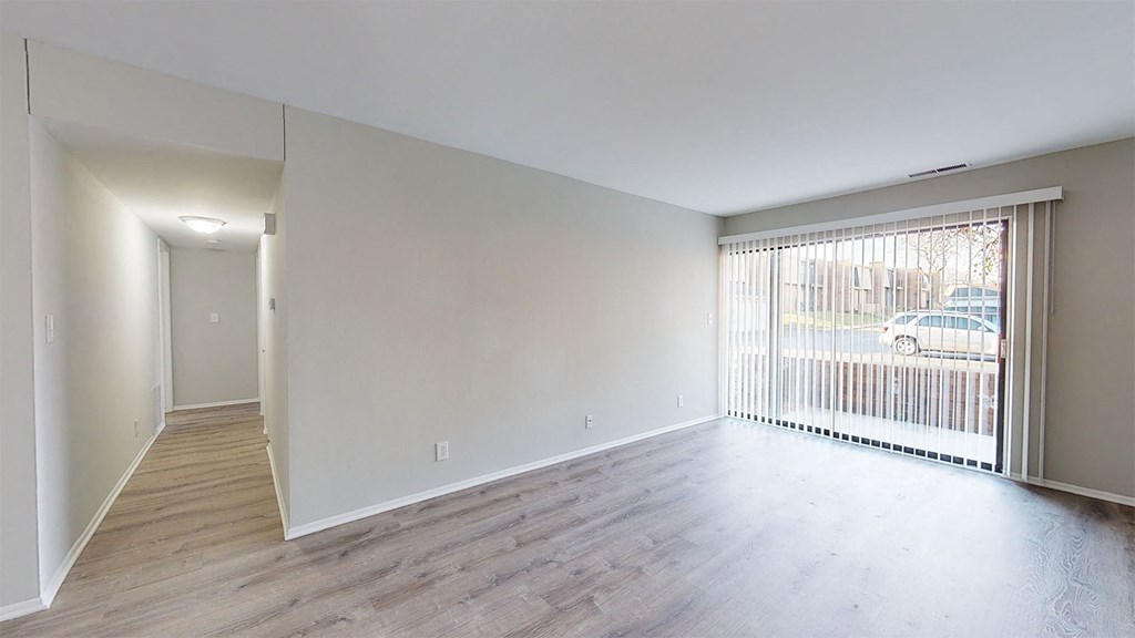a spacious living room with a large window and wood floors