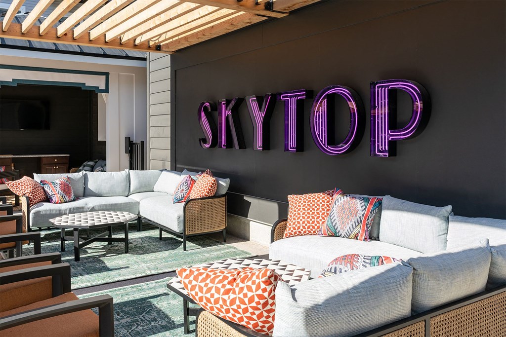 a living room with couches and chairs and a skytop sign on the wall