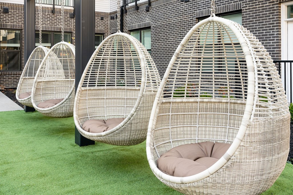 three hanging egg chairs in a row on a lawn