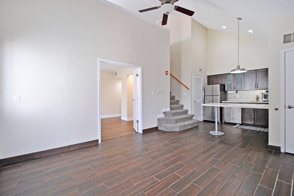 the living room and kitchen of a new home with a ceiling fan