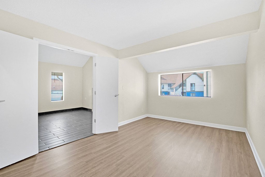 a spacious living room with wood flooring and white walls