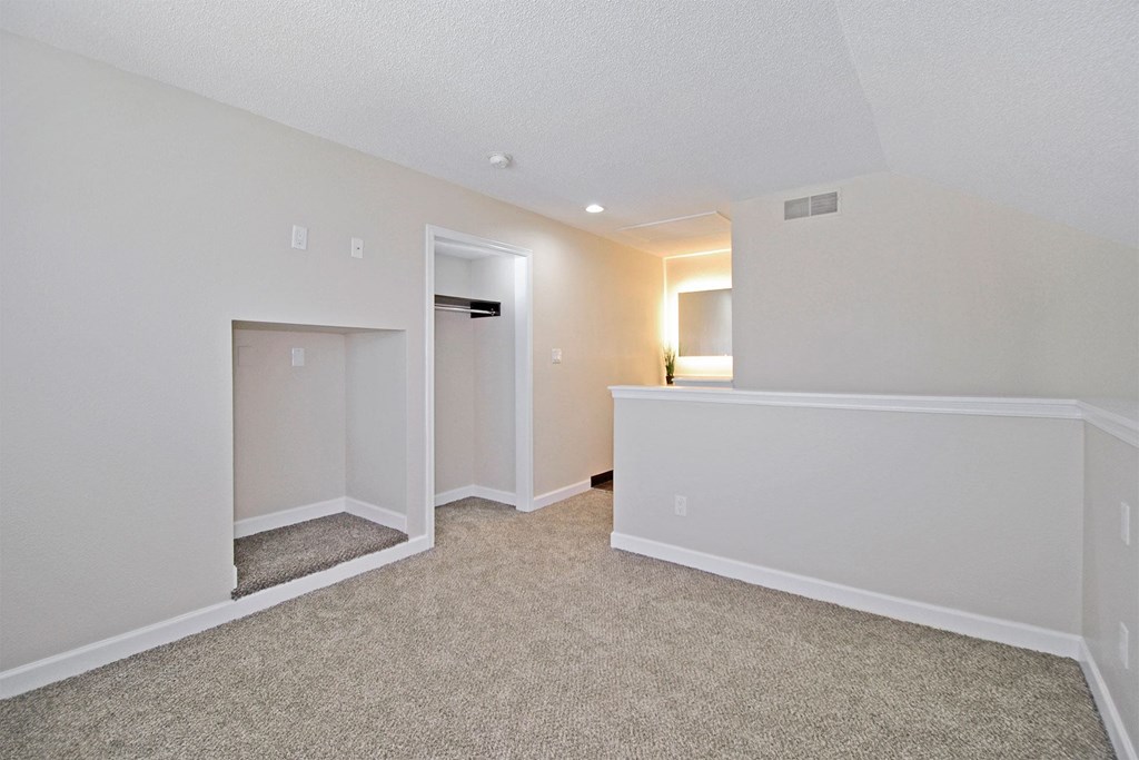 the spacious living room and dining room with white walls and carpet