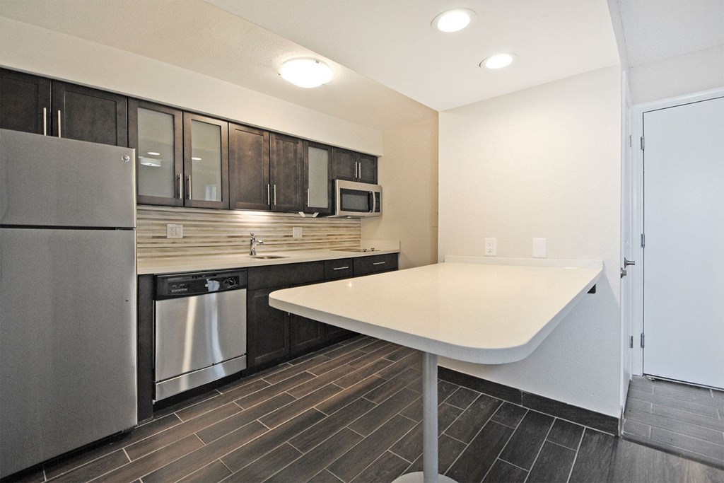 a kitchen with a white counter top and a stainless steel refrigerator