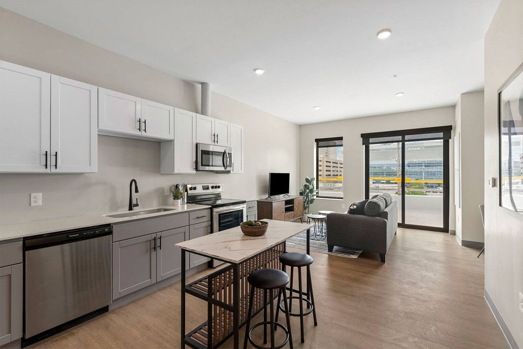 a kitchen and living room with white cabinets and a wooden floor