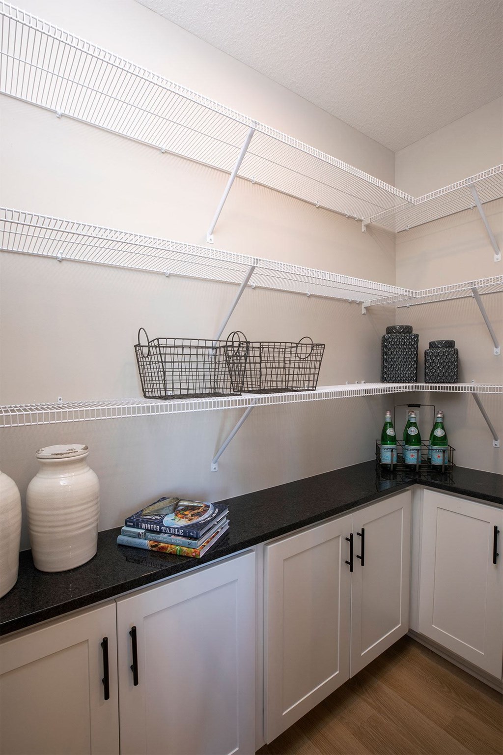 a laundry room with white cabinets and black countertops
