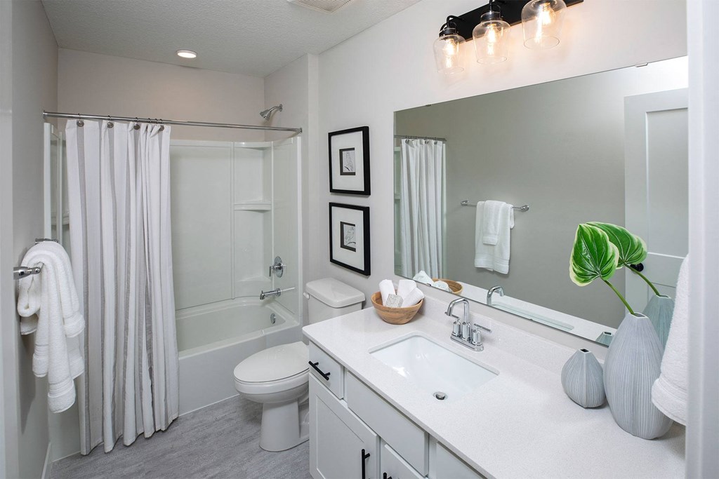 a bathroom with a white sink and toilet next to a white bathtub with a shower curtain