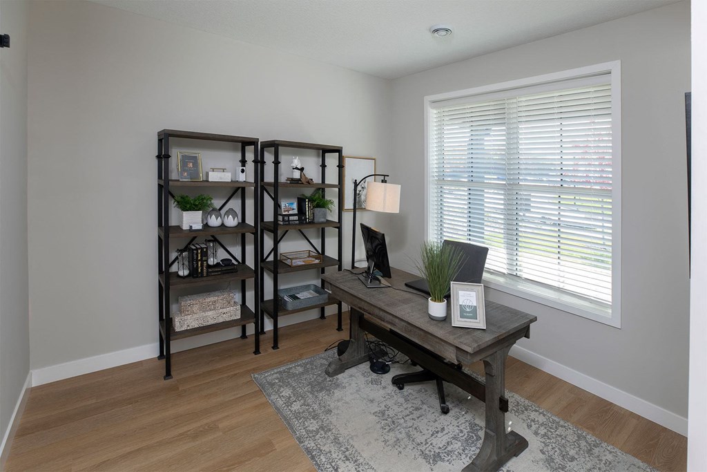 a home office with a large window and wooden floors