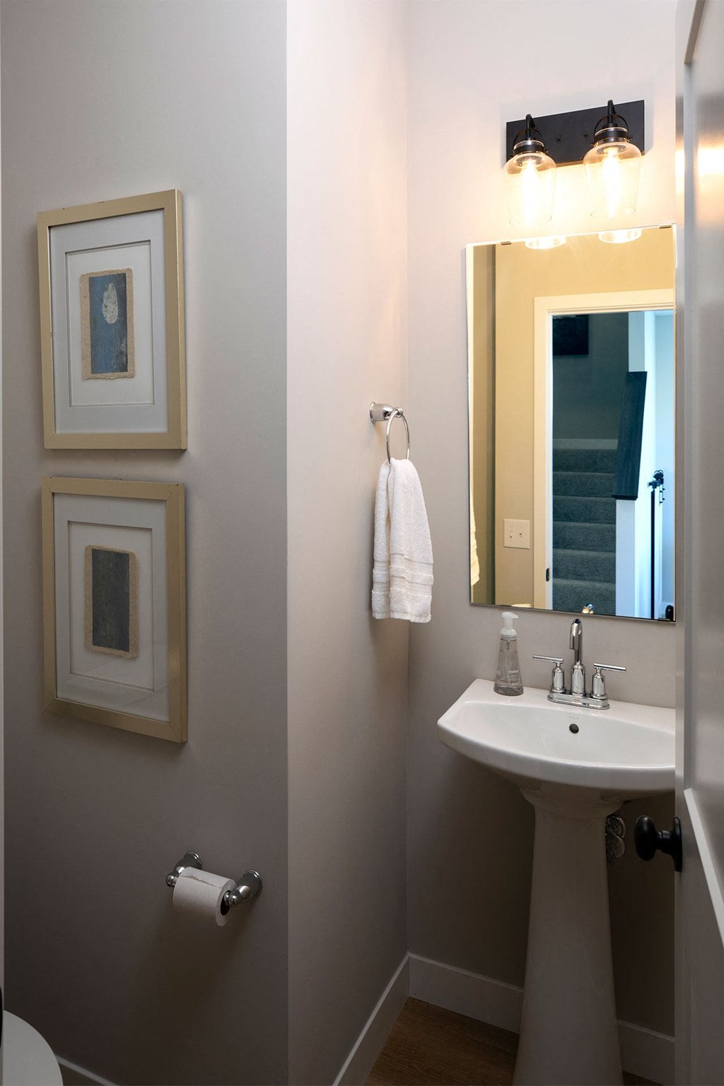 a small bathroom with a pedestal sink and a large mirror