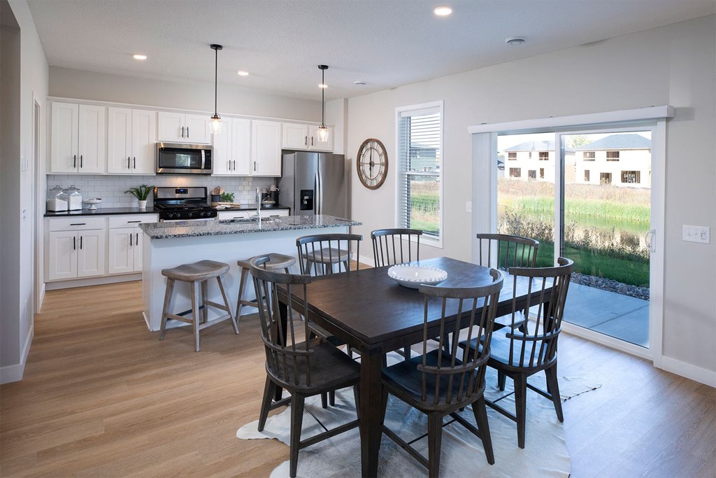 a dining area with a table and chairs and a kitchen in the background