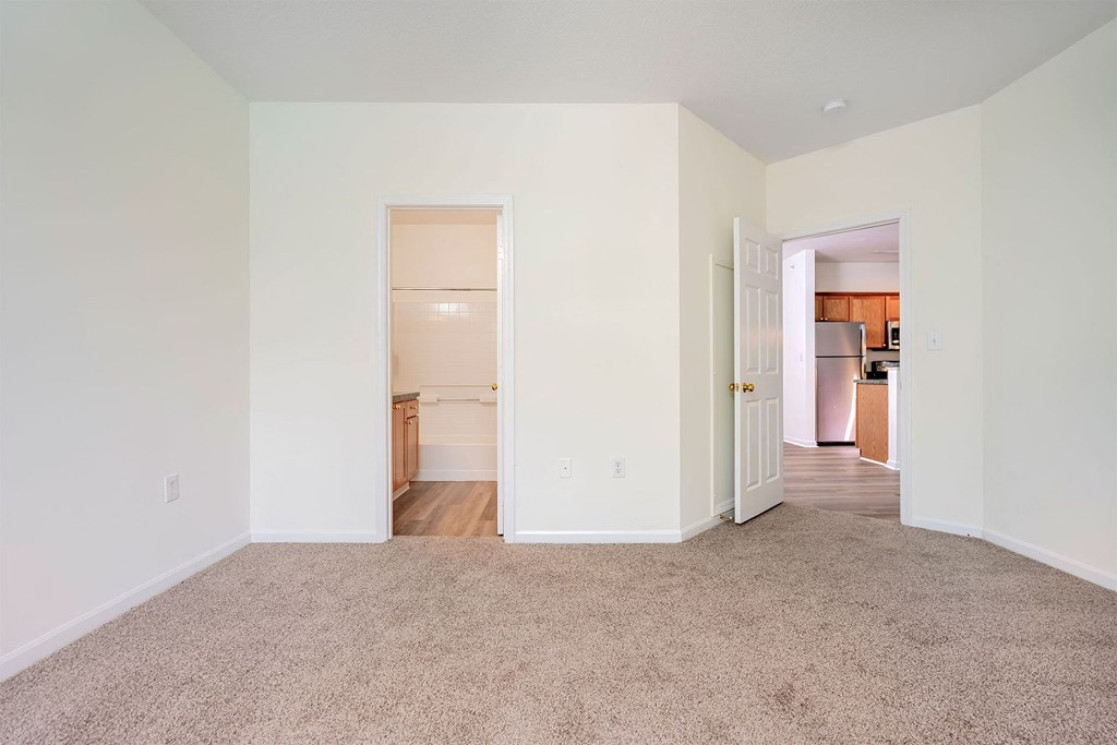 a living room with carpet and a door to a kitchen