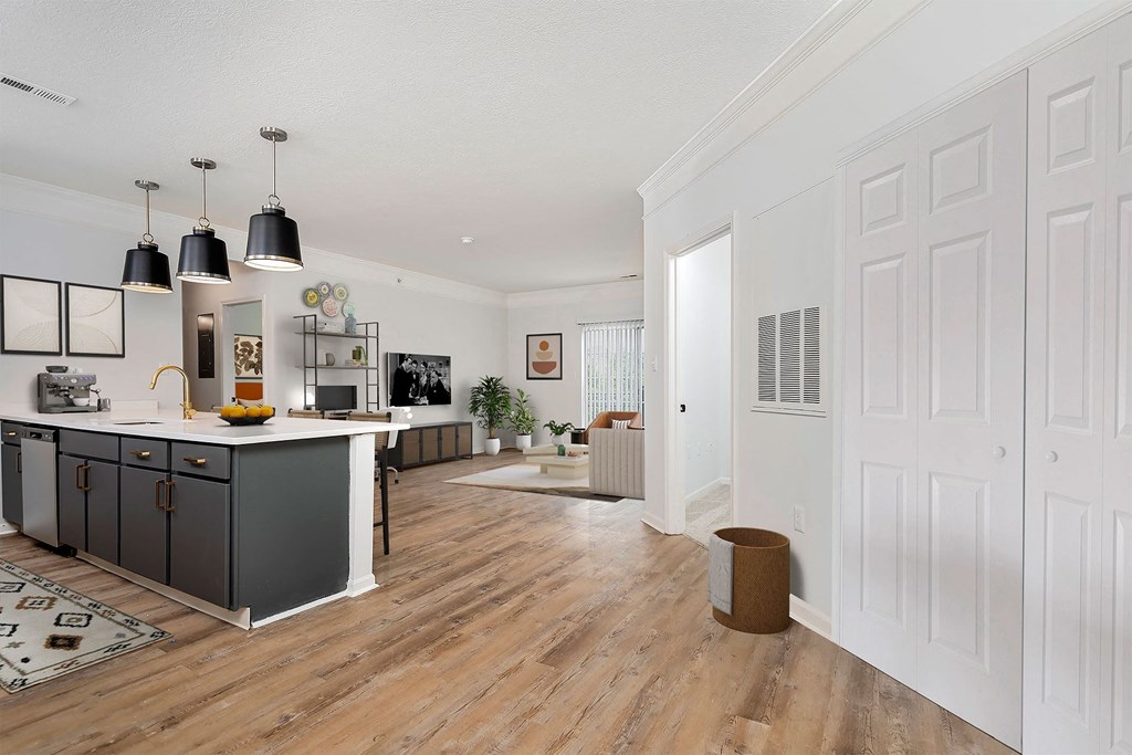 a kitchen and living room with white walls and wooden floors