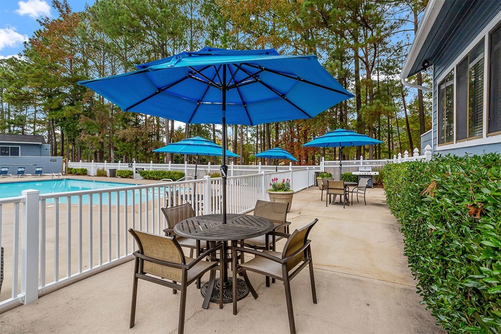 A blue umbrella is over a table with chairs.