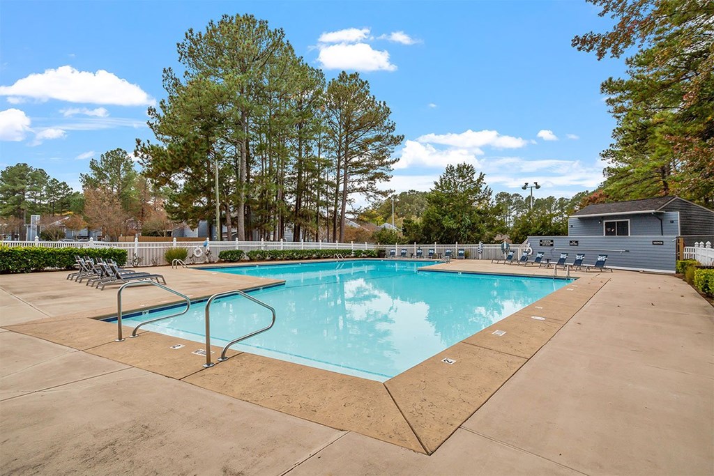 A swimming pool surrounded by trees and a small building.