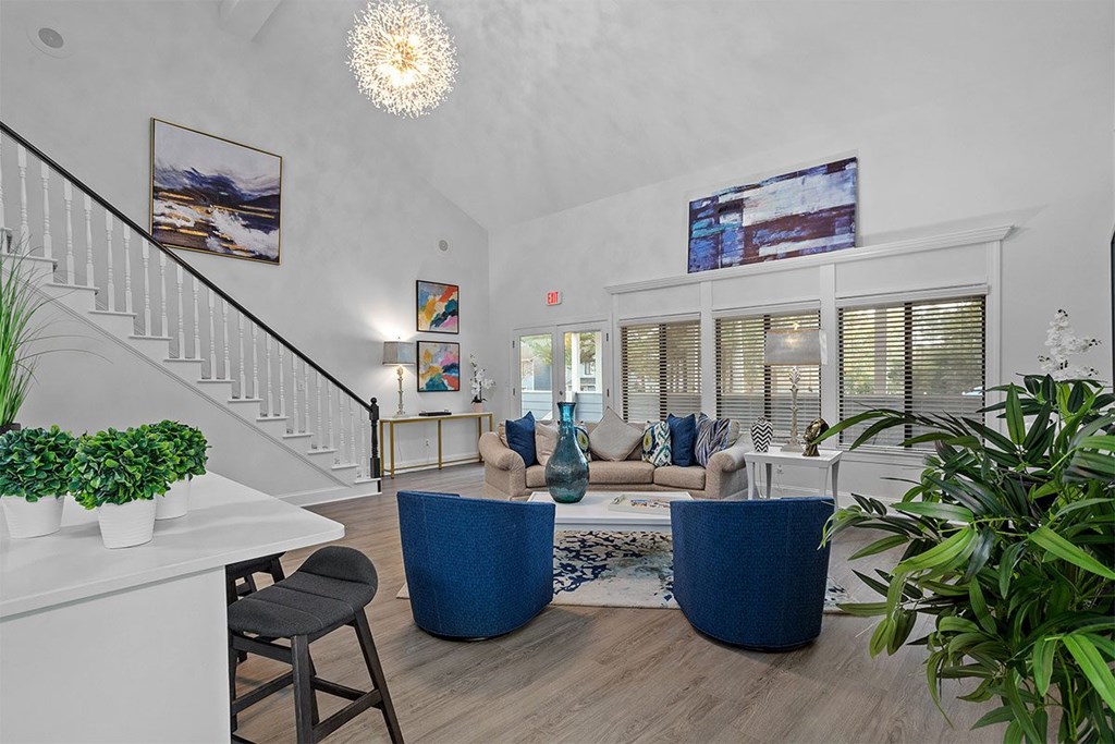 A living room with a staircase and a blue sofa.