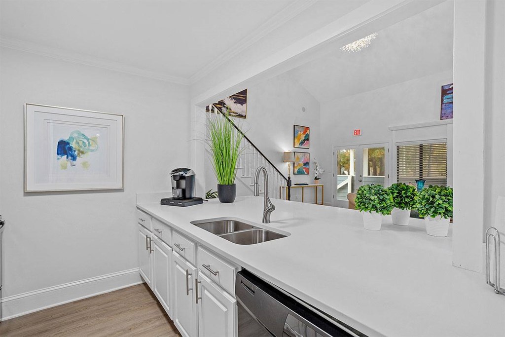 A white kitchen with a sink and a painting on the wall.