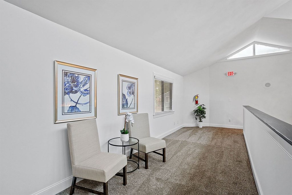 A room with two chairs and two framed pictures on the wall.
