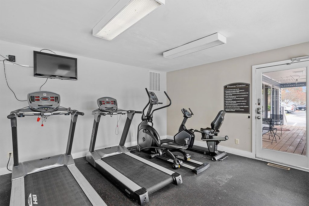 A gym with treadmills, elliptical machines, and a flat screen TV.