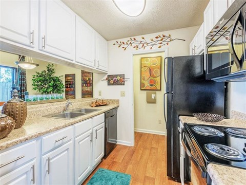 A kitchen with white cabinets and a black fridge.