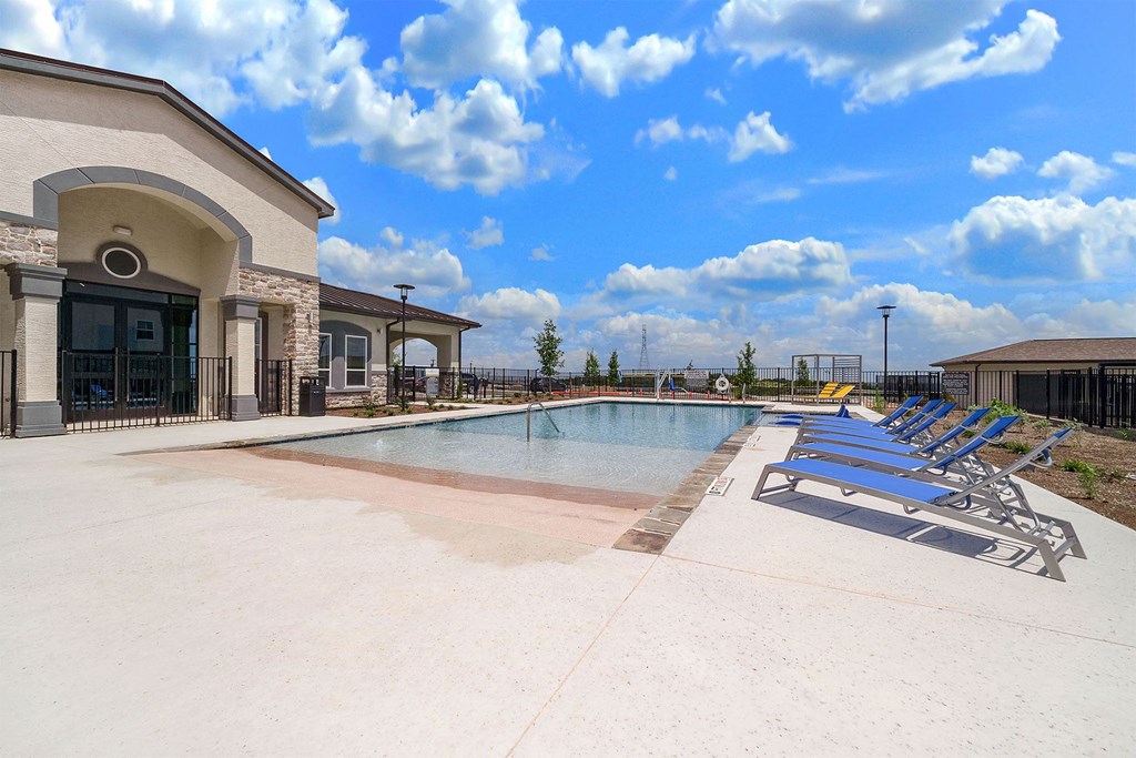 a swimming pool with chaise lounge chairs and a building in the background