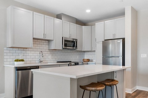 a kitchen with white cabinets and a white island with three stools
