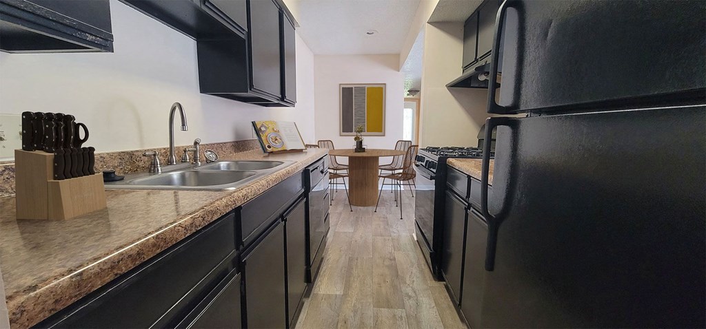 a kitchen with black appliances and counters and a dining room with a table