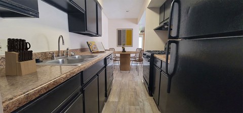 a kitchen with black appliances and counters and a dining room with a table