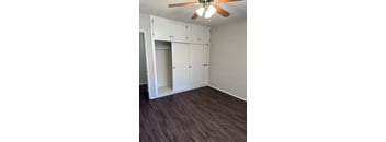 A room with a ceiling fan and built-in cabinets.