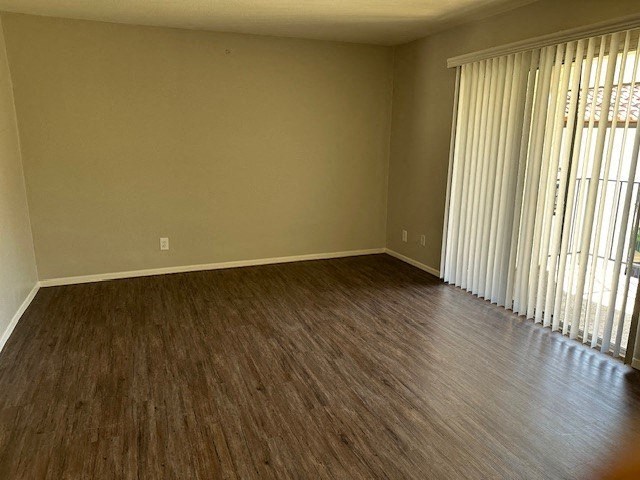 an empty living room with wood floors and a window