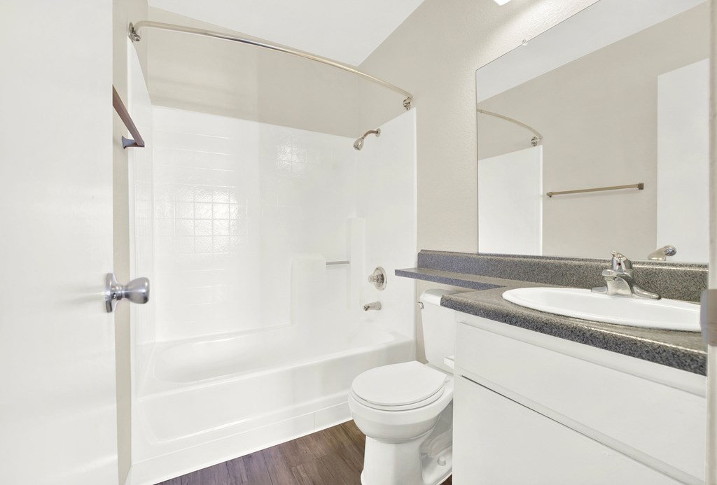 A white bathroom with a toilet, sink, and shower.