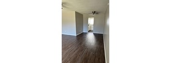 an empty living room with wood floors and a ceiling fan