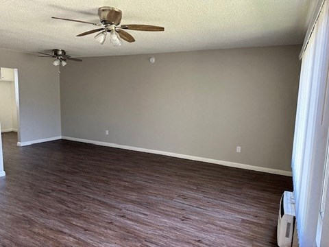 an empty living room with wood floors and a ceiling fan