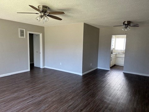 an empty living room with wood floors and a ceiling fan