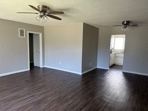 an empty living room with wood floors and a ceiling fan