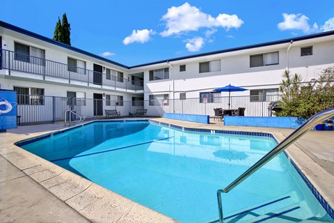 A swimming pool in front of a building with a blue sky in the background.