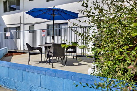 A blue umbrella is on a table outside a building.