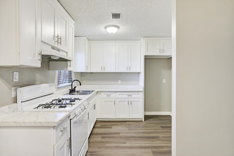 A kitchen with white cabinets and a white stove top oven.