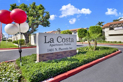 A sign for La Costa Apartment Homes stands in front of a building.