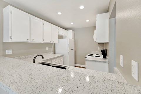 A kitchen with white cabinets and a granite countertop.